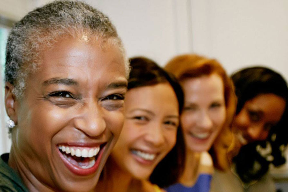 Four women of various ages and ethnicities smiling